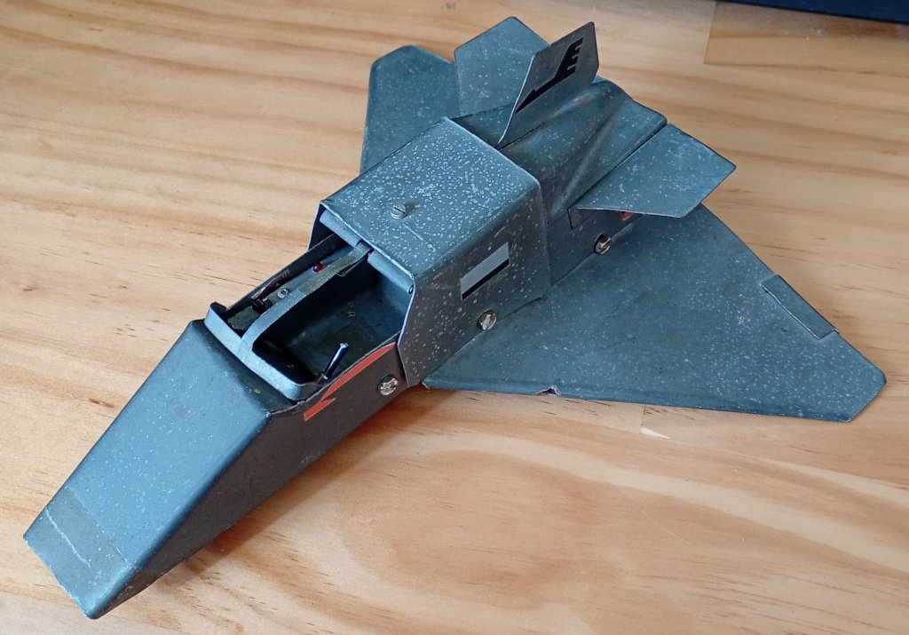 A toy jet aircraft made of galvanised steel sheet held together with screws and pop rivets. It is rather beaten up. 