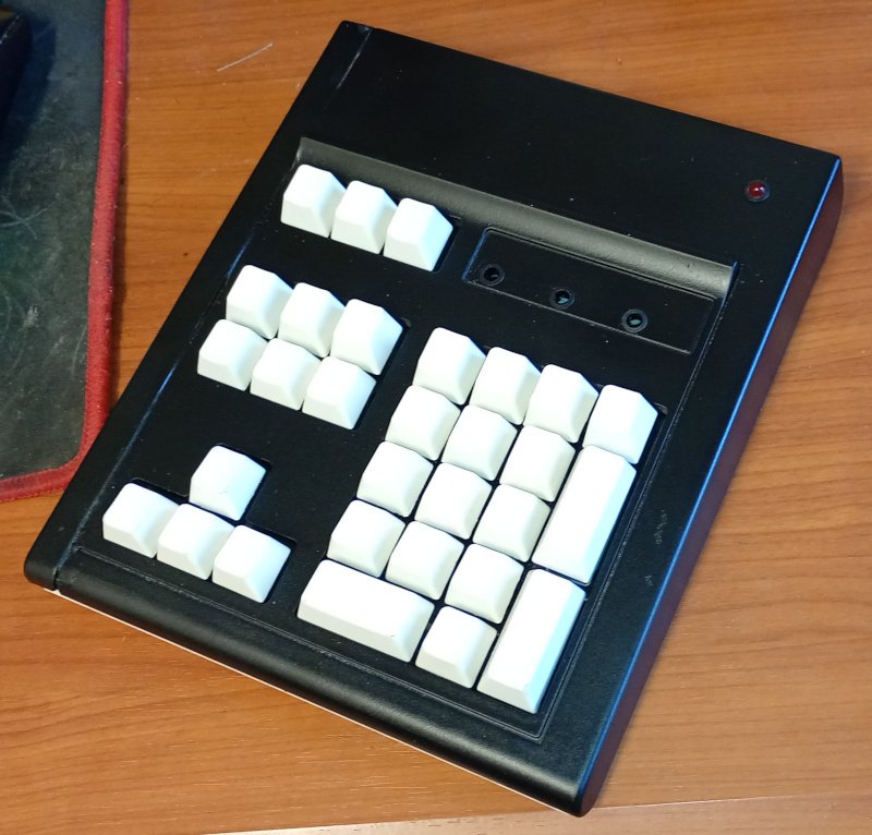 The picture shows a keypad made from the navigation keys and numpad of an old computer keyboard. The case is black and the keys are white with no labels. The status LEDs are missing but there is a new power LED in the top right corner of the case.