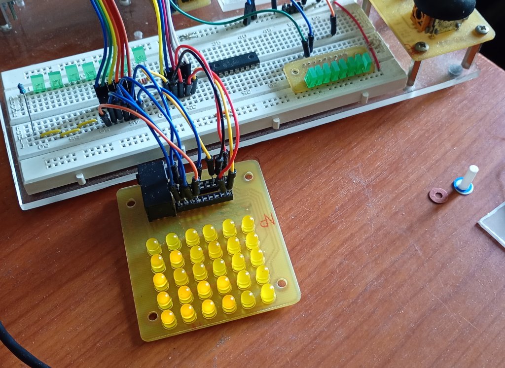The picture shows a desk top with an electronics breadboard populated with a bunch of coloured wires and LEDs. Some of the wires go out of frame to a Raspberry Pi Pico. The rest are pligged into an IC socket on a circuit board that has a 6 by 5 array of yellow LEDs. You can't really tell if they are on or not because of the lighting. 