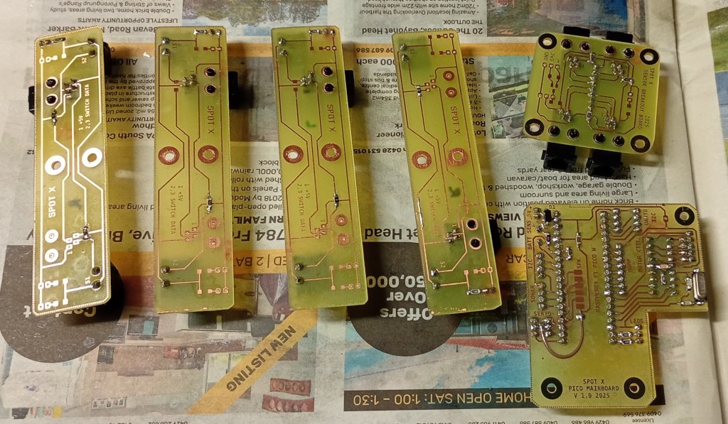 A picture of some circuit boards on a sheet of newspaper. The boards are in a variety of sizes and are sitting copper side up after being sprayed with circuit board lacquer.