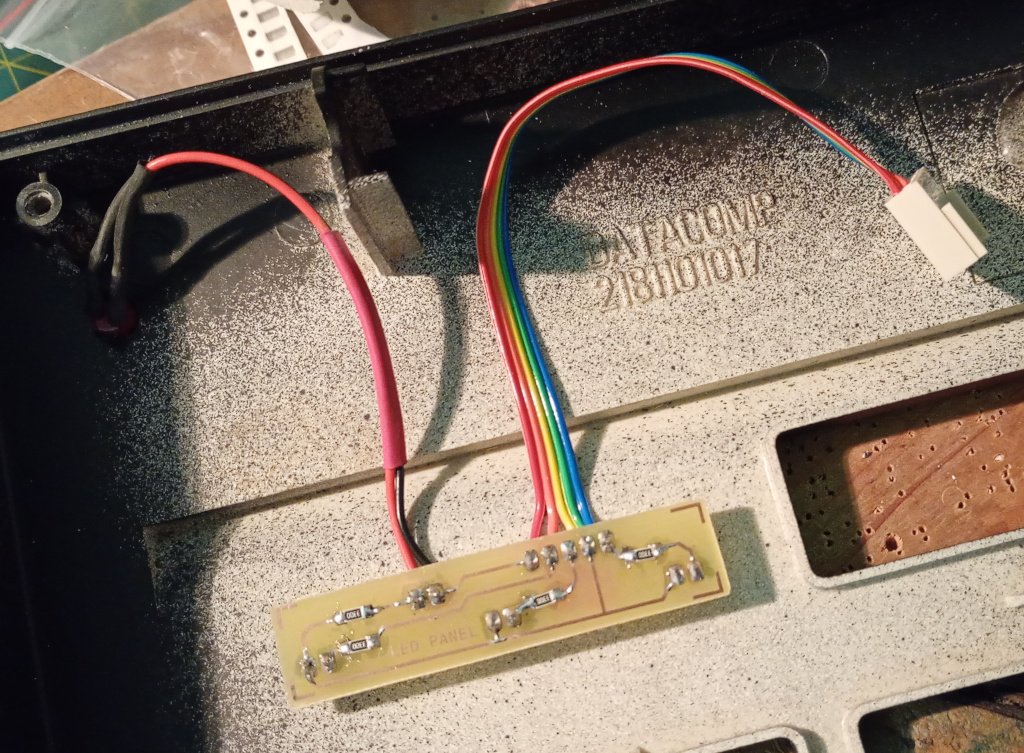 A picture of the inside of a keyboard case. A custom PCB has been fitted where the status LEDs would be. One pair of wires goes to a power LED and a length of colourful ribbon cable curls away to a header pin plug that connects to the microcontroller controlling the keypad. The keyboard was originally manufactured by Datacomp.