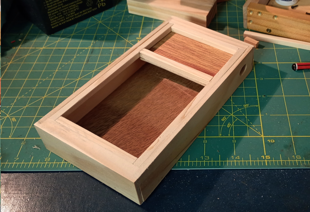 The finished box with the lid on. The lid leaves about 2/3 of the box open, which is where the keys will be. The remaining third is filled with a piece of plywood. It is on a craft mat.
