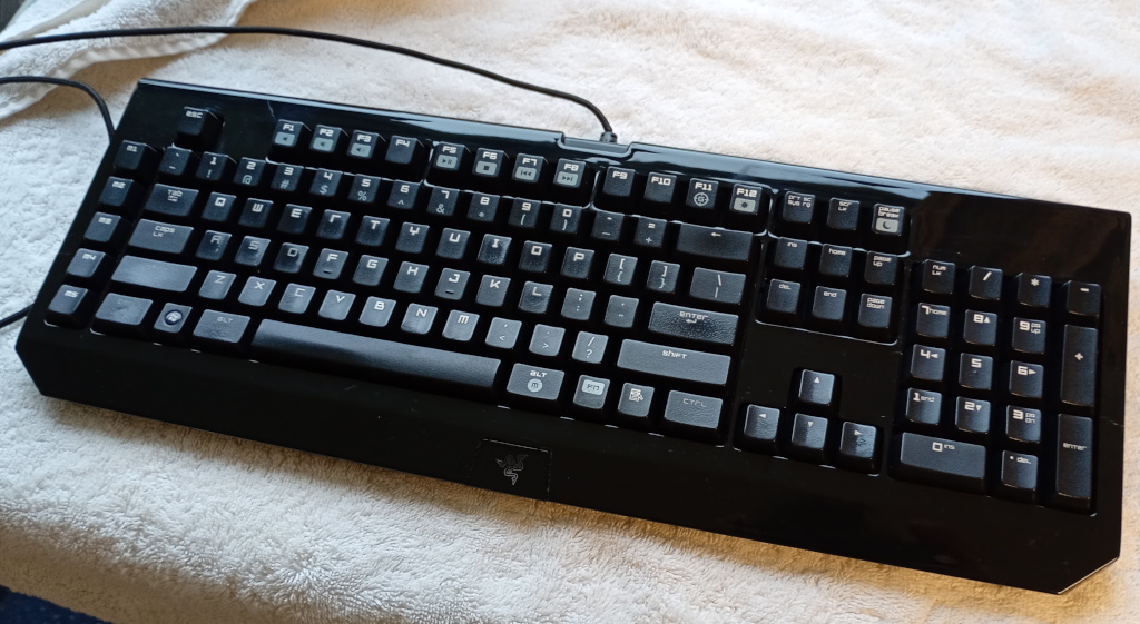 A cleaned black Razer Blackwidow keyboard sits on a fluffy white towel after being stripped down and cleaned by its neglectful owner.
